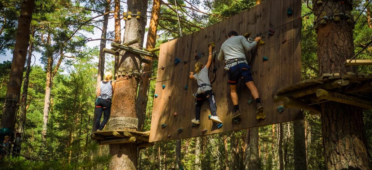 Family enjoying an outdoor climbing adventure in Cercedilla, Madrid amidst lush greenery.