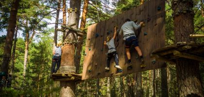 Family enjoying an outdoor climbing adventure in Cercedilla, Madrid amidst lush greenery.