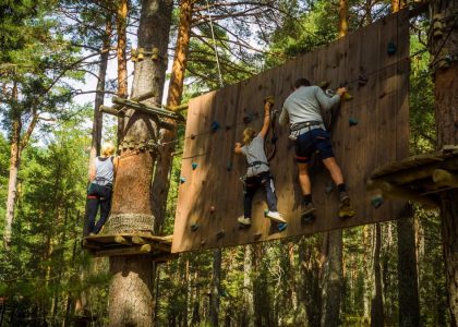 Family enjoying an outdoor climbing adventure in Cercedilla, Madrid amidst lush greenery.